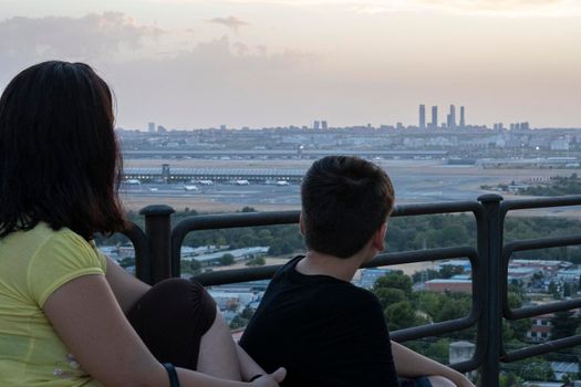 mom and son together enjoying Madrid airport and skyline views in a viewpoint.