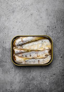 Close up and top view of canned sardine in a tin over gray rustic concrete background. Tinned fish as a convenient, fast, healthy food and source of omega-3 fatty acids, protein and vitamin D