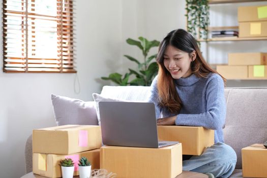 Startup SME small business entrepreneur of freelance asian woman using a laptop with box Cheerful success online marketing packaging box and delivery SME