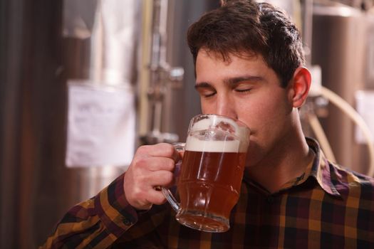 Close up of a man smelling aromatic freshly brewed craft beer in a mug