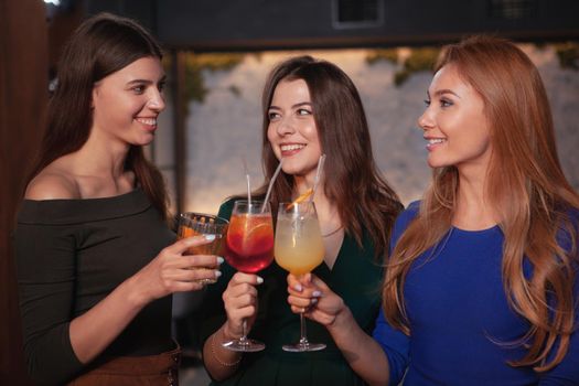Group of cheerful women celebrating at thebar, having cocktails together. Celebration, entertainment, friendship concept