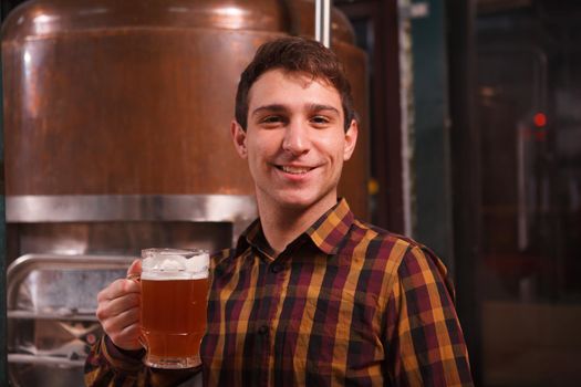 Happy young professional brewer smiling, holding beer mug