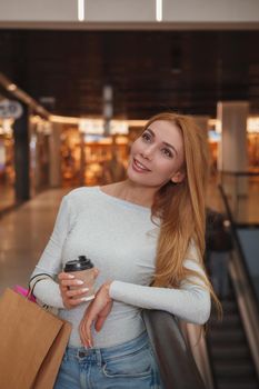 Vertical shot of a gorgeous young woman smiling, having coffee while shopping at the mall