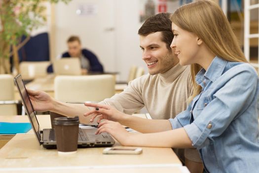Beautiful young woman smiling working on the laptop together with her male colleague coworkers students learning education project startup creativity technology gadget device internet online browsing