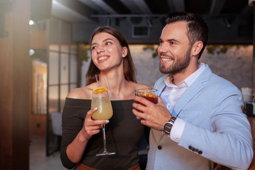 Happy couple laughing, celebrating at the bar. Happy handsome man and his girlfriend having fun at nightclub. Celebration, anniversary concept