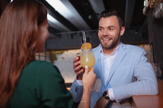 Handsome young man enjoying date with his girlfriend at cocktail bar. Couple having drinks at cocktail bar