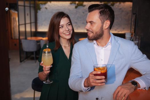 Charming young woman flirting with handsome young man at cocktail bar. Affection, love, dating concept
