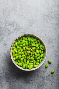 Fresh ripe green edamame beans without pods in bowl on gray stone background. Top view, close up. Light and healthy asian snack good source of vegetarian protein for diet and nutrition