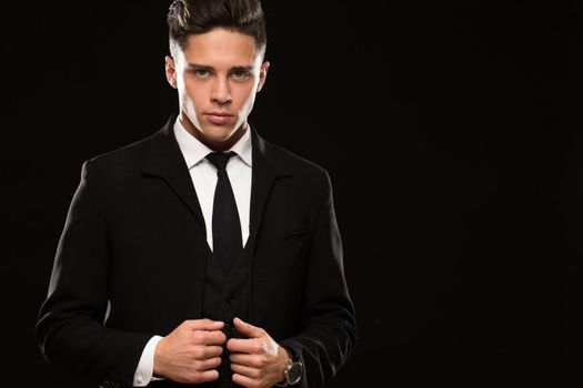 Shot of a sexy handsome young secret agent wearing elegant classy black suit looking to the camera seductively black background copyspace businessman fierce confident masculine brutality