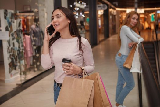 Cheerful woman talking on the phone while walking at shopping mall