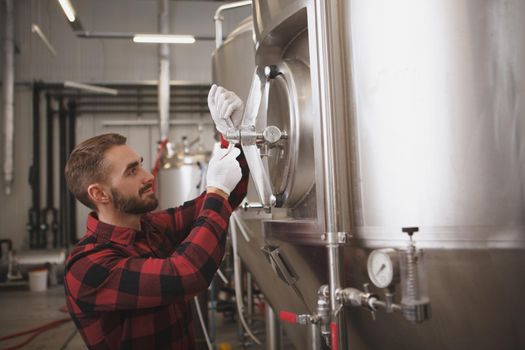 Attractive male brewer closing beer tank at his microbrewery