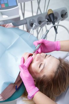 Vertical top view shot of a mature woman getting professional dental cleaning at dentists office