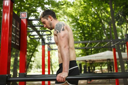 Profile shot of sportsman doing triceps dips outdoors