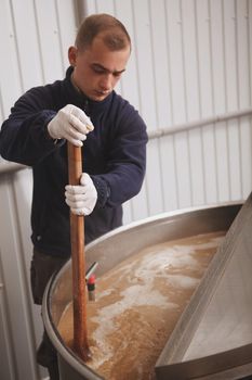 Vertical shot of a professional brewer controlling beer fermentation process at beer factory