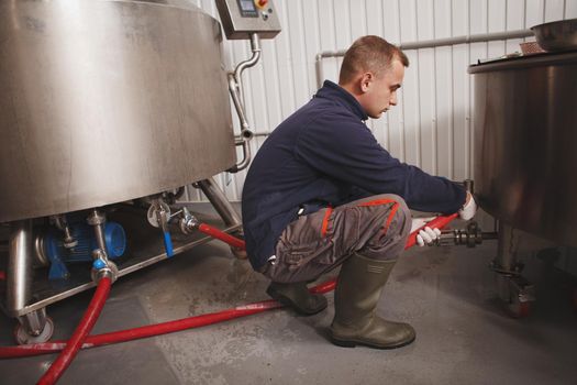 Full length shot of a worker preparing microbrewery equipment for beer brewing