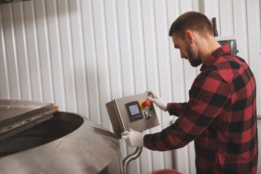 Rear view shot of a professional brewer operating beer fermentation automated tank at his microbrewery