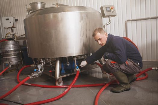 Maintenance worker examining microbrewery equipment