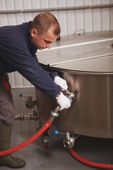 Vertical cropped shot of a maintenance worker fixing fermentation beer tank at craft beer factory