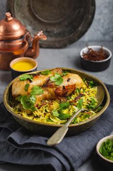 Biryani chicken, traditional dish of Indian cuisine, with basmati rice, fried onion, fresh cilantro in bowl on gray rustic stone background. Authentic Indian meal, close-up, selective focus