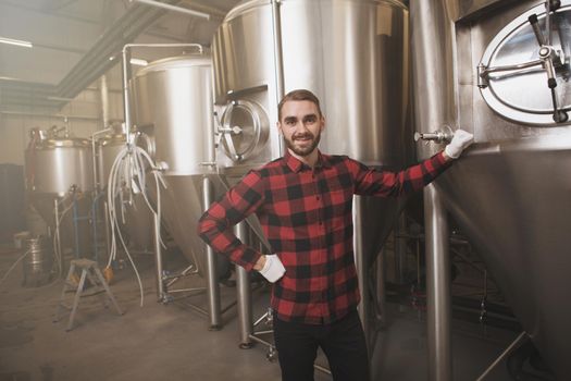 Happy handsome brewer smiling proudly, working at beer factory