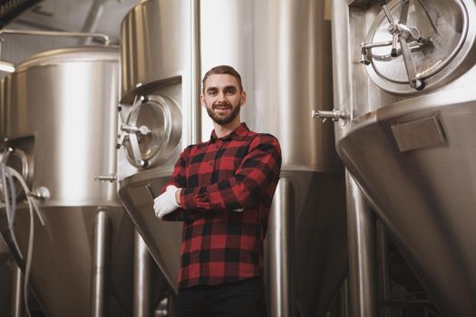 Cheerful successful brewer posing at his microbrewery