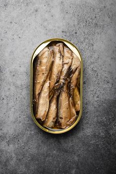 Close up and top view of smoked canned sardine in a tin over gray rustic concrete background. Tinned fish as a convenient, fast, healthy food and source of omega-3 fatty acids, protein and vitamin D