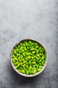 Fresh ripe green edamame beans without pods in bowl on gray stone background with space for text. Top view, close up. Light and healthy asian snack good source of protein for diet and nutrition