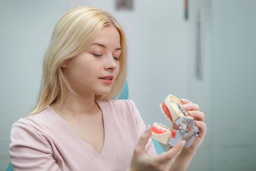 Attractive woman looking at dental mold waiting for teeth examination by dentist