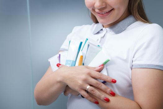 Cropped shot of female dentist hugging bunch of toothpaste tubes, copy space