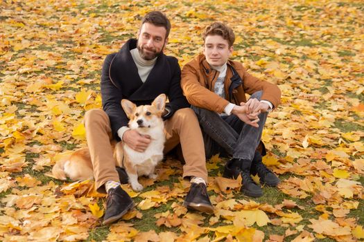 Father and son with a pet on a walk in the autumn park.