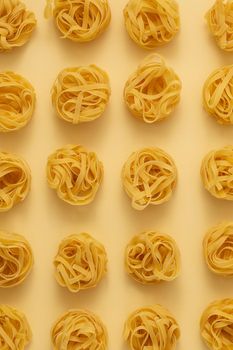 Minimal food pattern made of pasta tagliatelle on light yellow pastel background. Close up of traditional Italian pasta in pop art style. Pasta, Italian cuisine concept. Top view, flat lay