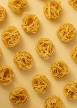 Minimal food pattern made of pasta tagliatelle on light yellow pastel background. Close up of traditional Italian pasta in pop art style. Pasta, Italian cuisine concept. Top view, flat lay