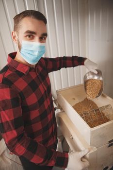 Professional brewer wearing medical mask, working at his brewery