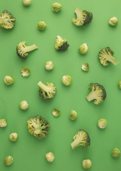 Green vegetables food pattern made of broccoli and Brussels sprouts on green background. Creative minimal flat lay design about nutrition, healthy eating, diets, vitamins. Top view