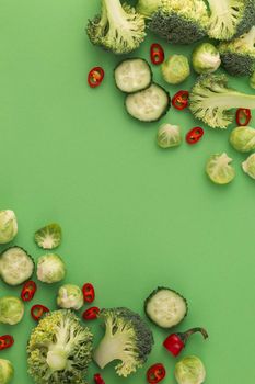 Vegetables food pattern made of broccoli, Brussels sprouts, cucumber, chili pepper, green background. Minimal flat lay design of nutrition, healthy eating, diets, vitamins. Top view, space for text