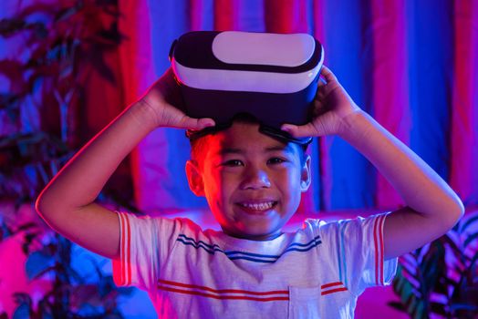 Little kid boy experiencing virtual reality goggles experiencing reality, Child open VR helmet glasses from eyes excited and smiling purple and blue background, Virtual technology