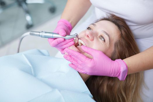 Mature woman having professional dental cleaning done by dentist