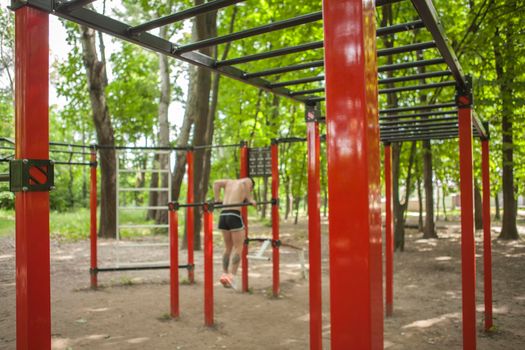 Selective focus on calisthenics playground equipment, man doing dips on bars on background