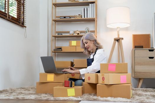 Asian woman entrepreneurs wokring at home with many parcel bxes, Small business Startup Ideas. SME or freelance business online and delivery concept