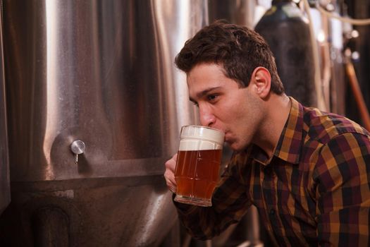 Close up of a professional brewer sipping delicious craft beer freshly brewed at his microbrewery