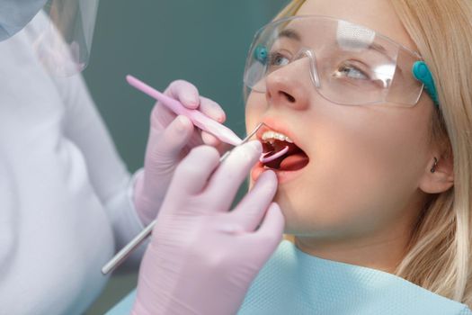 Female patient wearing protective glasses while getting dental treatment at the clinic