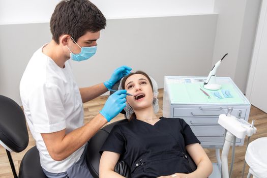 Dentist examining patient teeth with mirror in dentist clinic. Having dental checkup