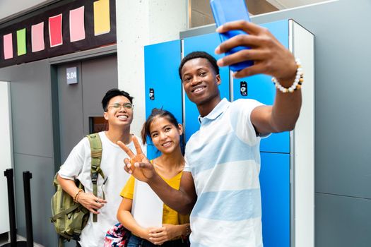 Happy group of teen multiracial classmate take a selfie in high school corridor next to lockers. Friendship concept. Back to school concept.