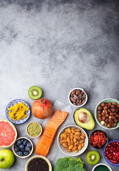Selection of healthy products and superfoods: salmon, fruit, vegetables, berries, goji, spirulina, matcha, quinoa, chia, nuts with copy space. Clean eating concept, gray background, top view, close up