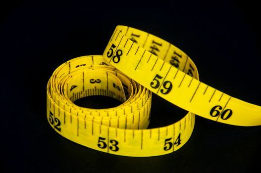 Measuring tape on dark background with customizable space for text. Copy space and weight loss concept.