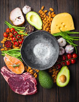 Empty rustic bowl with low carbs ingredients for clean eating and weight loss, copy space, top view. Keto foods: meat, fish, avocado, cheese, vegetables, nuts. Ketogenic diet concept, healthy fats