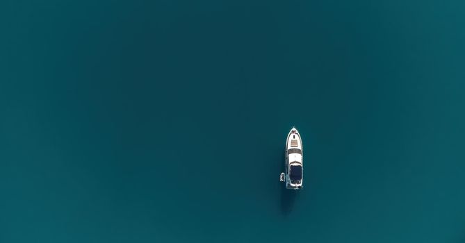 Aerial boat race. Luxury cruise trip. View from above of white boat on deep blue water. Aerial view of rich yacht sailing sea. Motor boat racing wave. Summer journey on luxury ship