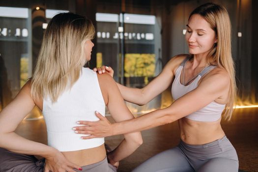 Yoga exercises. A personal trainer teaches a woman yoga classes in the gym.