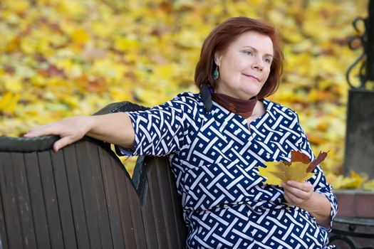 Elderly woman with autumn leaves.Autumn age