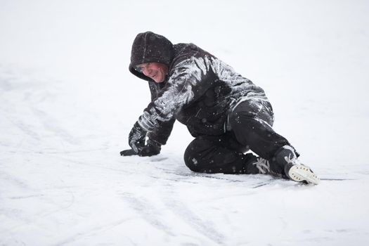 The man fell on skates in the snow.An elderly man learns to ride a hockey skate